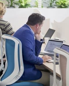 Man in blue blazer working at laptop in office.