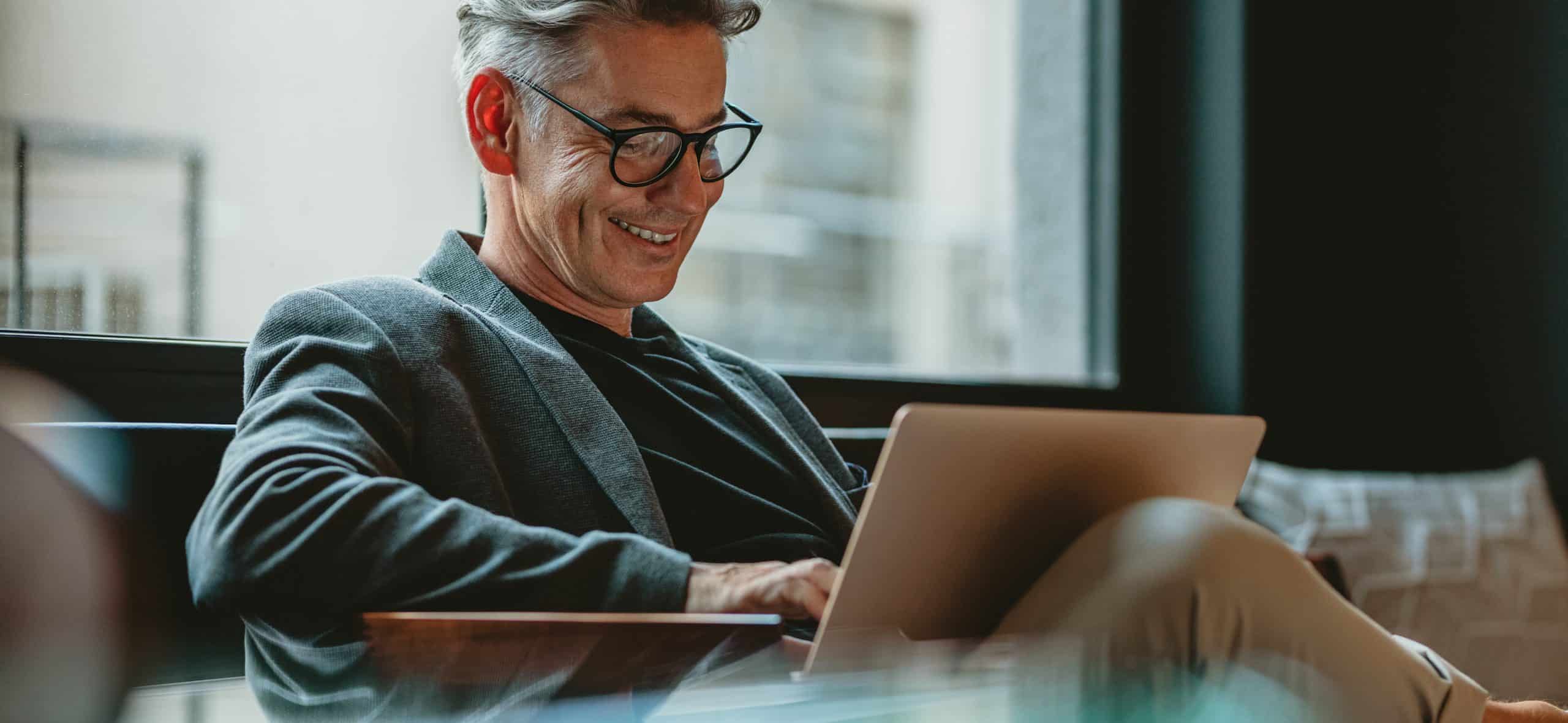 Man smiling while using a laptop indoors