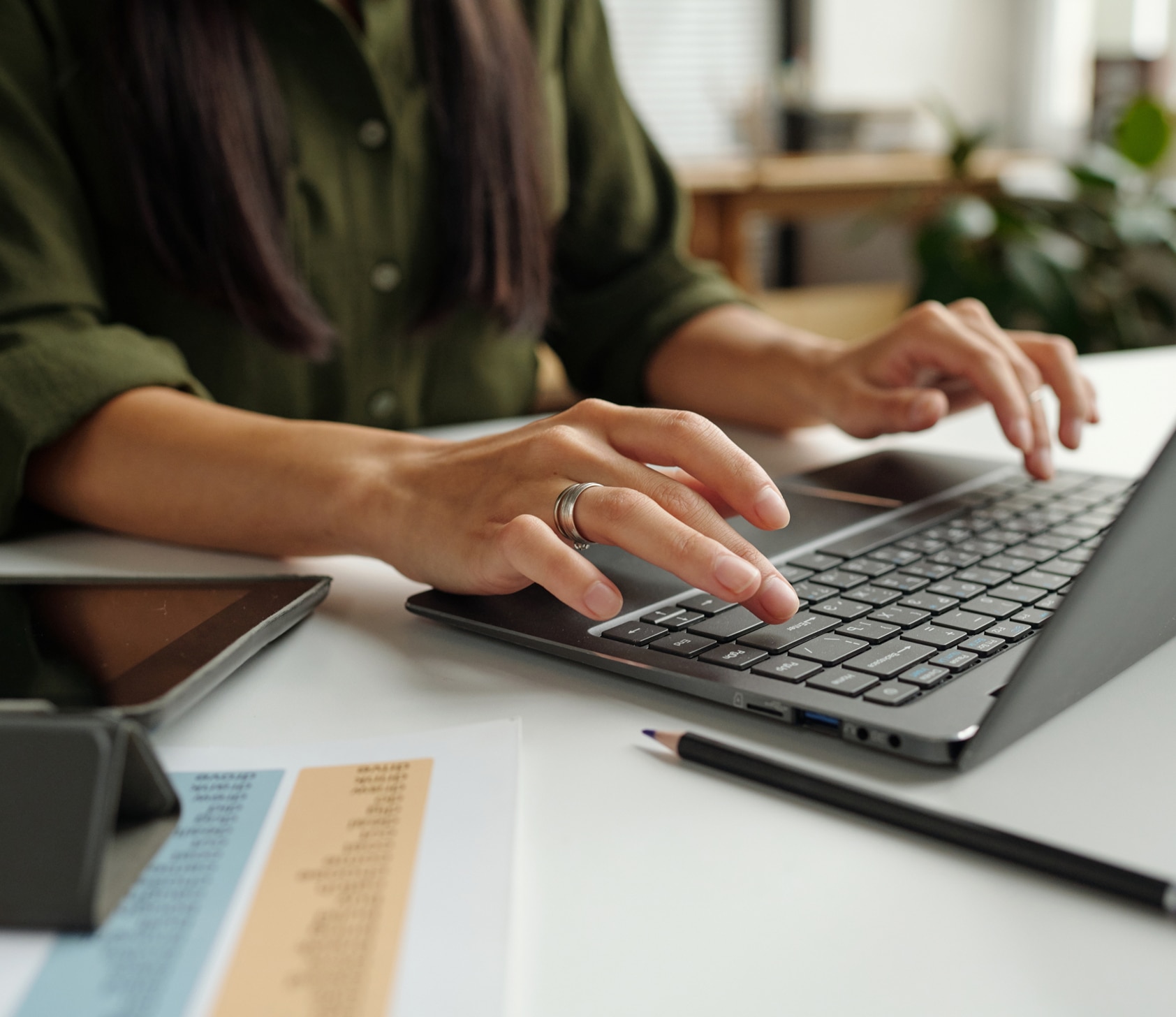 Person typing on laptop at desk with documents