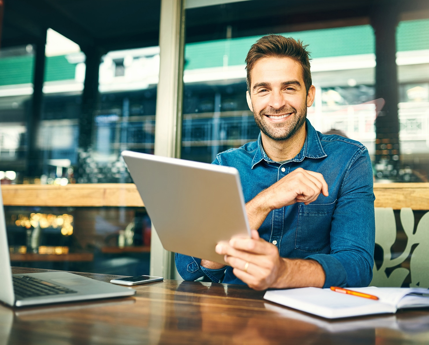 Smiling man using tablet at café