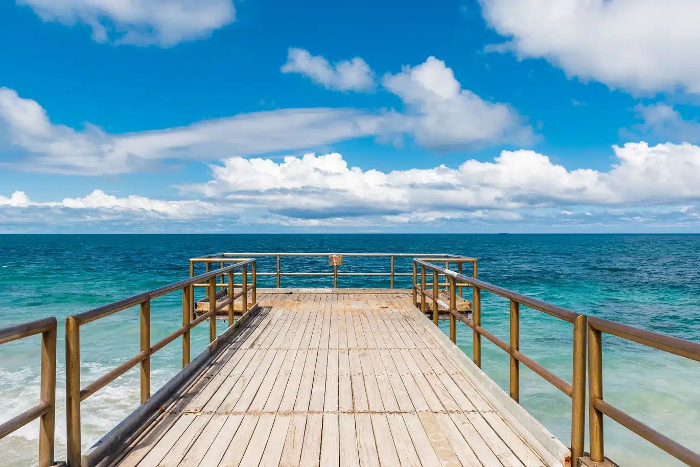 Wooden pier extending into the ocean under clouds.